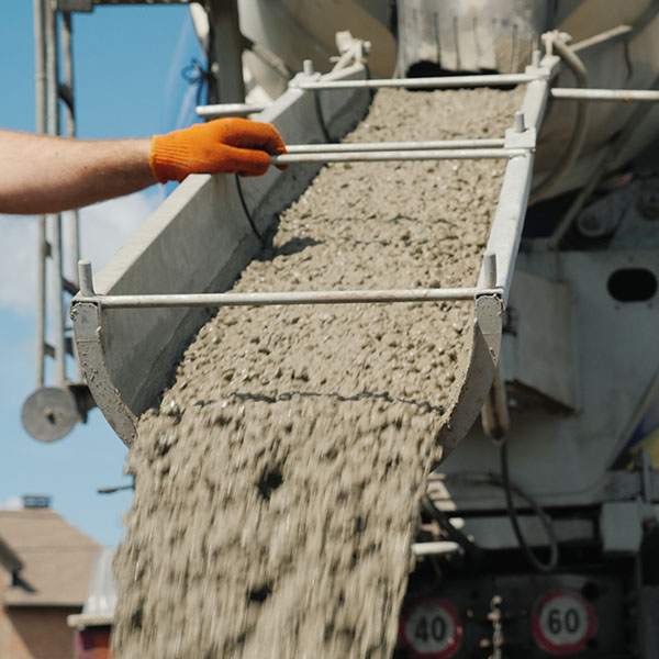 Work on pouring the foundation, the worker directs the chute from which the concrete flows